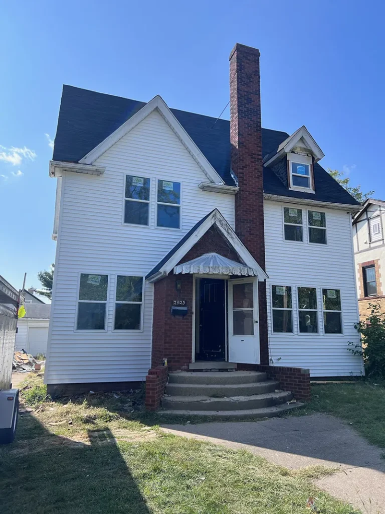 Two-story house with white siding, a brick chimney, and a covered front porch.