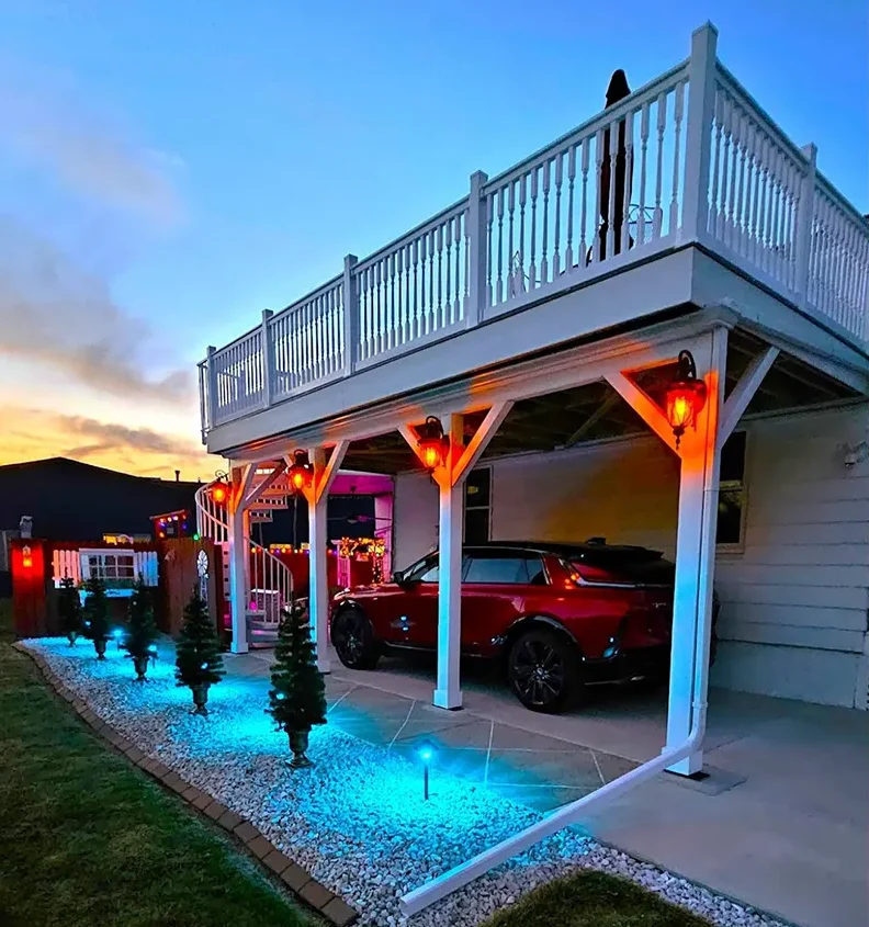 House exterior at dusk with vibrant blue pathway lighting and orange accent lights on the porch columns.