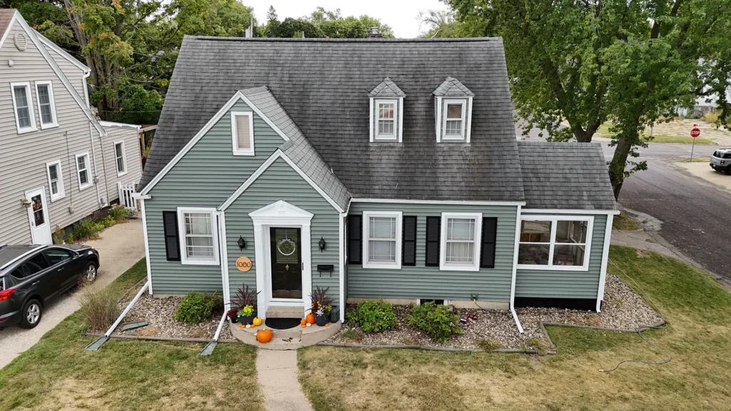 A house with light green siding and black shutters.