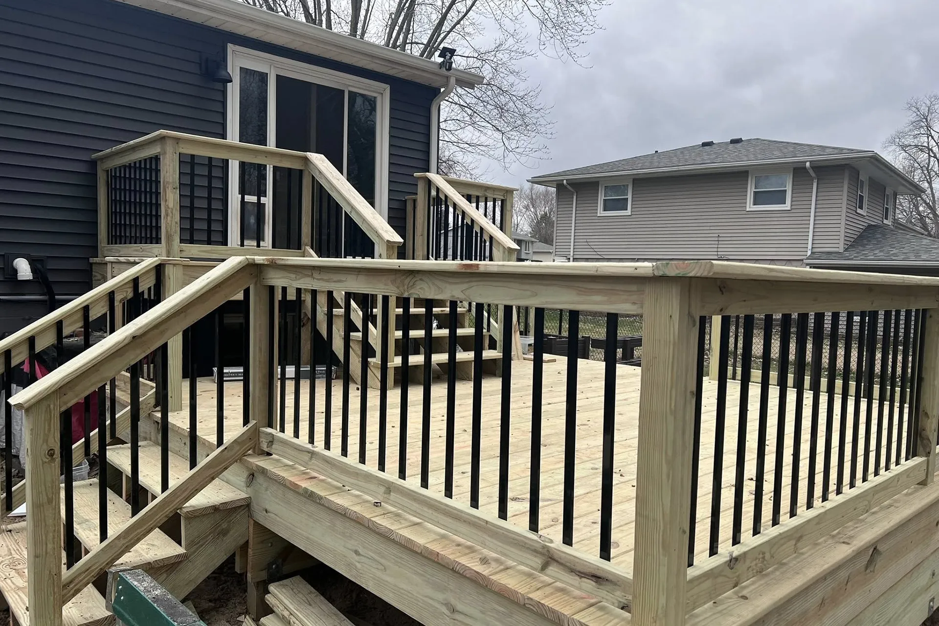 A newly constructed wooden deck with light-colored lumber and black metal balusters.