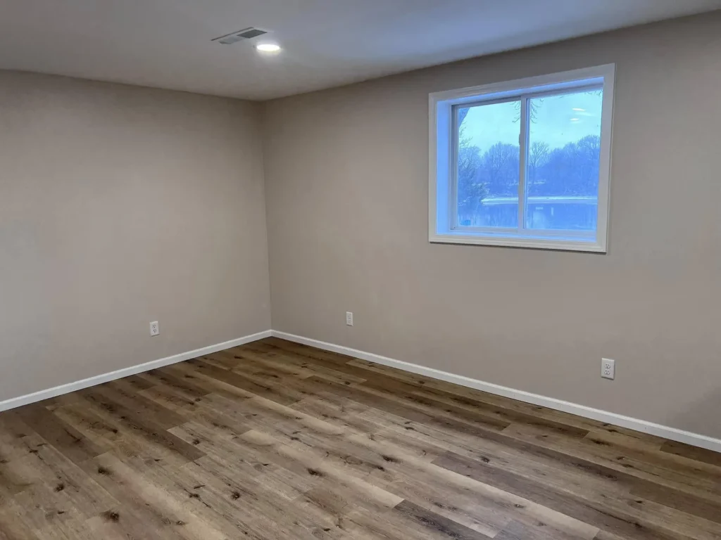 Canton, IL Best Construction A freshly renovated room with light brown walls and new wood-look laminate flooring.