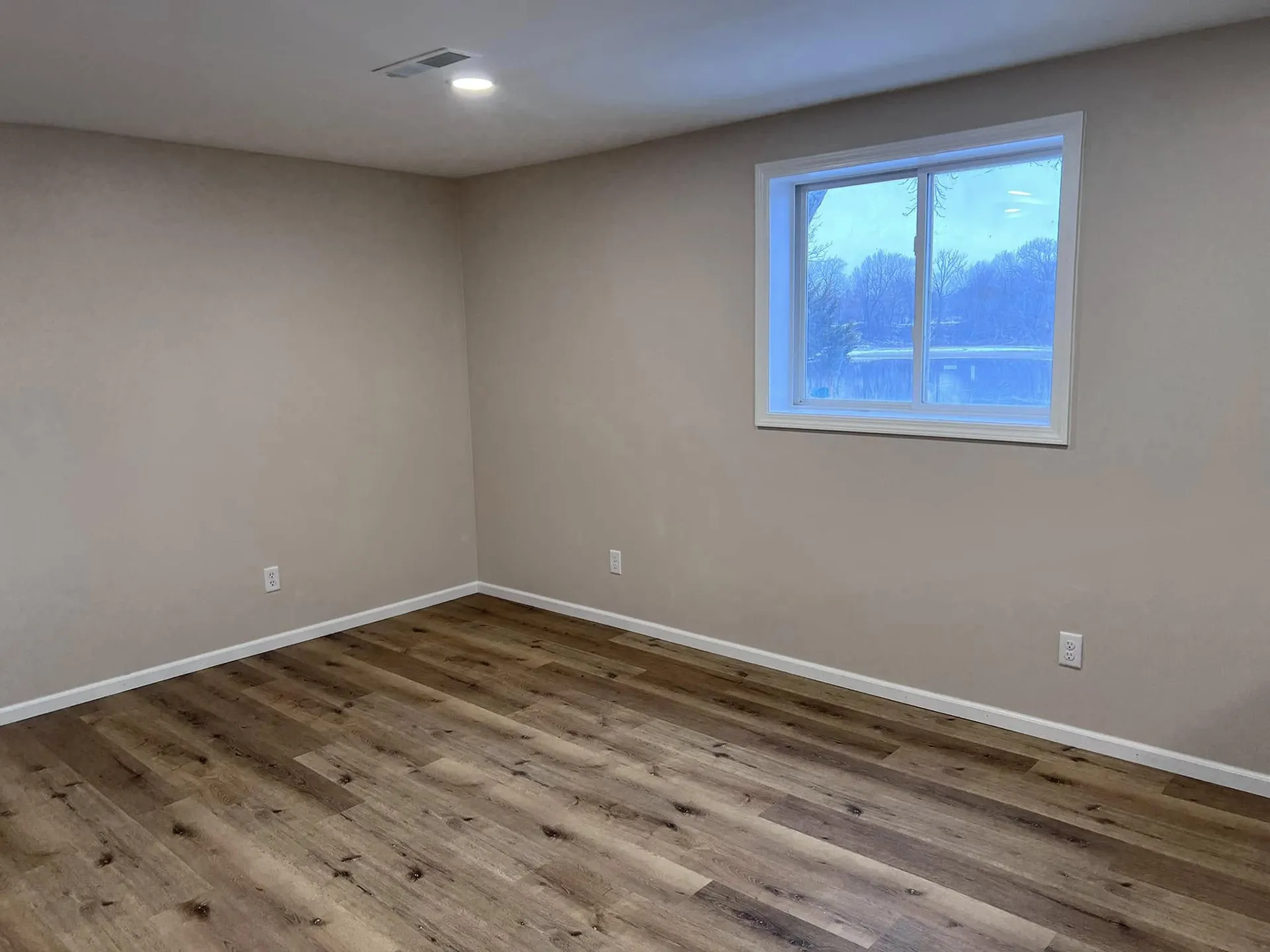 Canton, IL Best Construction A freshly renovated room with light brown walls and new wood-look laminate flooring.