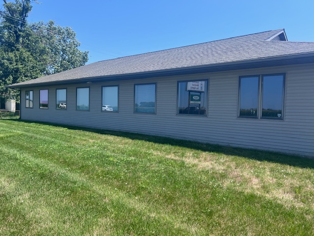 Exterior of a house addition with new blue vinyl siding and newly installed white framed windows, with construction materials around.