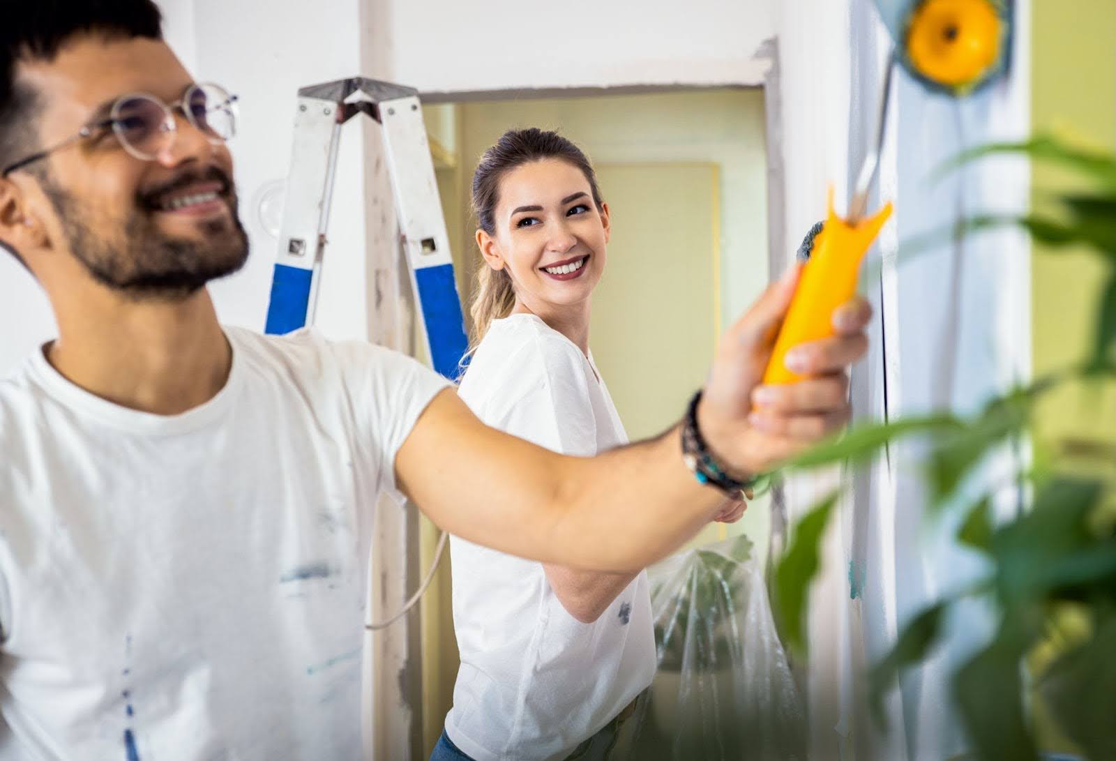 A couple are happily painting the inside of their home.