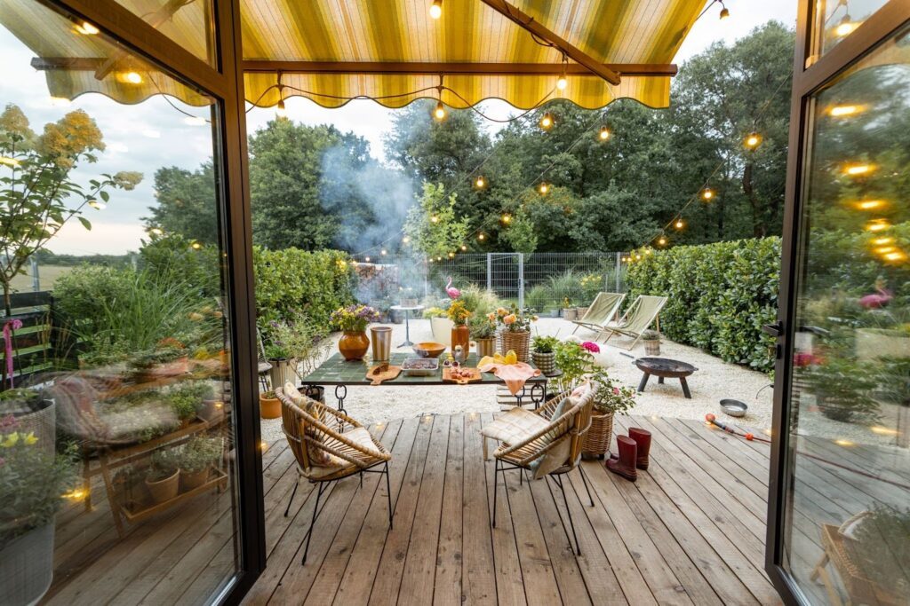 Cozy garden deck at dusk with a warm-lit dining area and soft ambient lighting.