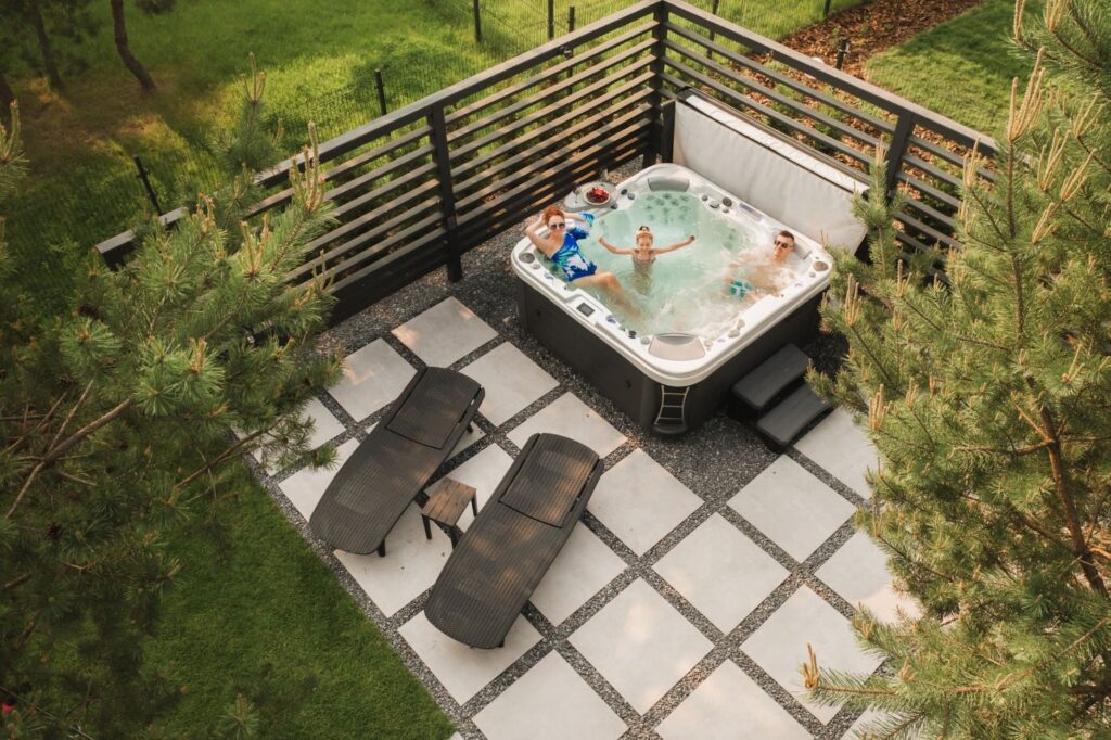 Overhead shot of a family in a hot tub on a railed deck with two pool beds nearby.