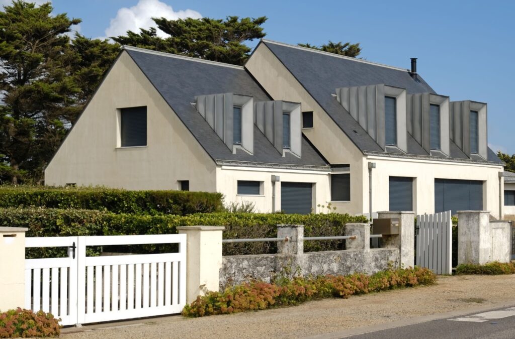 Coastal-style house with a solid concrete fence and a vinyl gate in the front yard.