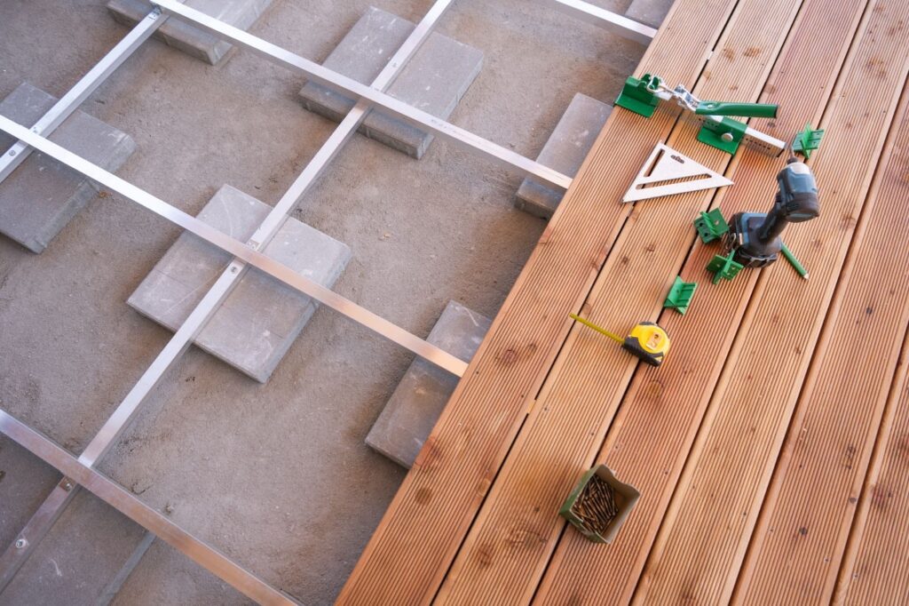 Wooden deck surface with tools and deck materials laid out for outdoor construction preparation.