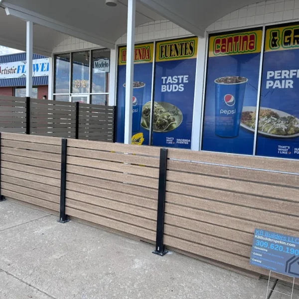 New brown and gray composite horizontal slat fencing for a restaurant patio with a sign for KB Builders LLC