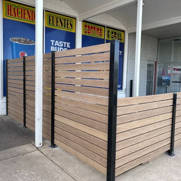 Outdoor patio with modern horizontal slat composite fencing in front of a restaurant