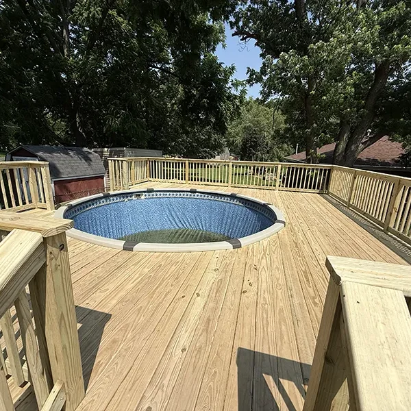 New wood deck surrounding a round above-ground pool in a backyard