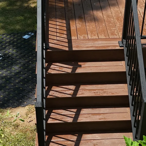 Close-up of new brown composite deck stairs with black metal railing and balusters