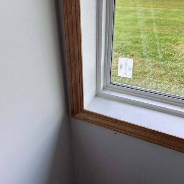 Close-up of a newly installed window with white frame and a custom wooden interior trim.
