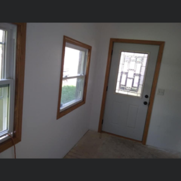 Interior view of a room with newly installed windows with wooden frames and a white glass-paneled door.