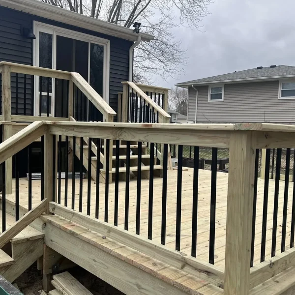 A newly constructed wooden deck with light-colored lumber and black metal balusters.