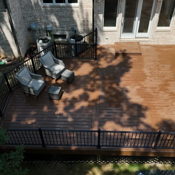 Elevated view of a residential backyard with a new brown composite deck and black metal railing